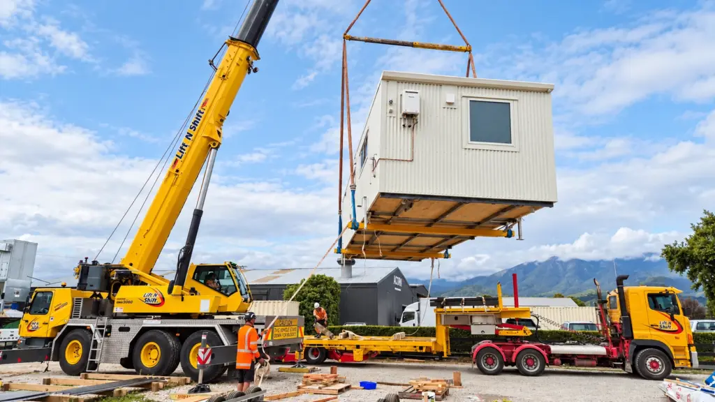 Crane lifting a completed modular tiny home into position on site