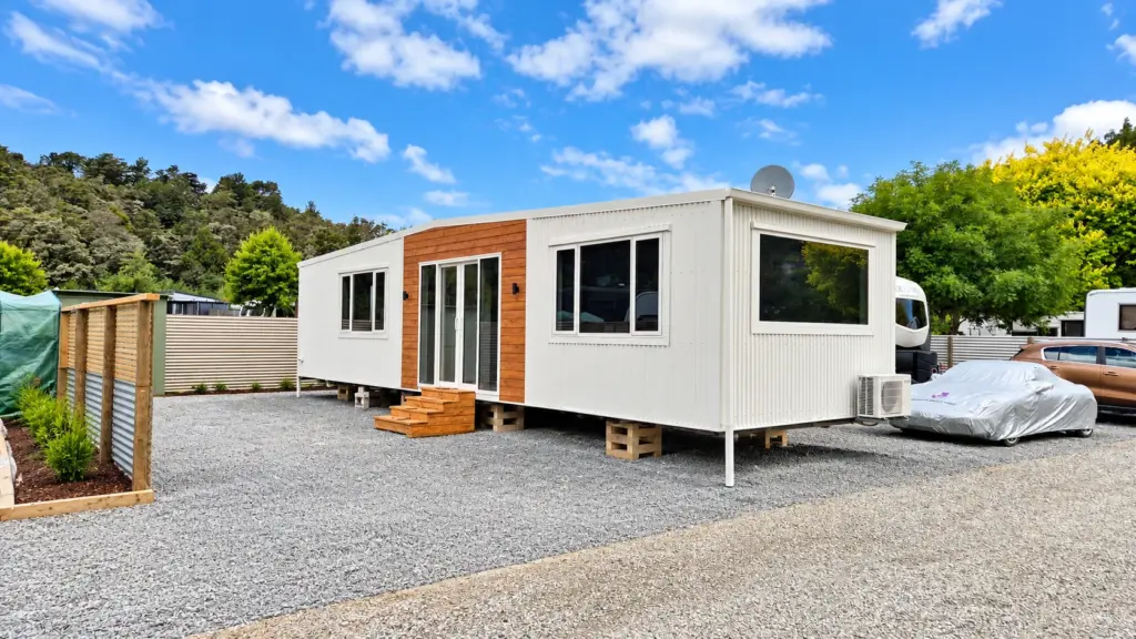 Custom tiny home with white cladding and macrocarpa features in a holiday park setting