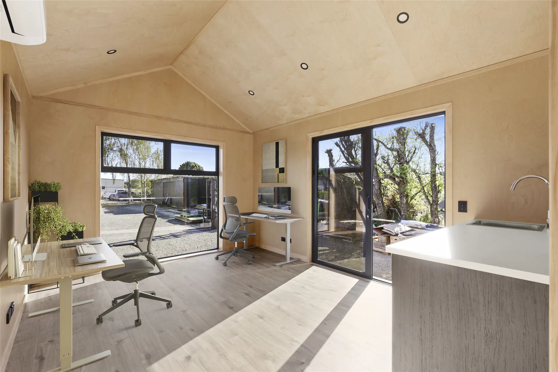 Inside a Cosy Cabins For Play cabin set up as a home office and sleepout with timber lining and a large window