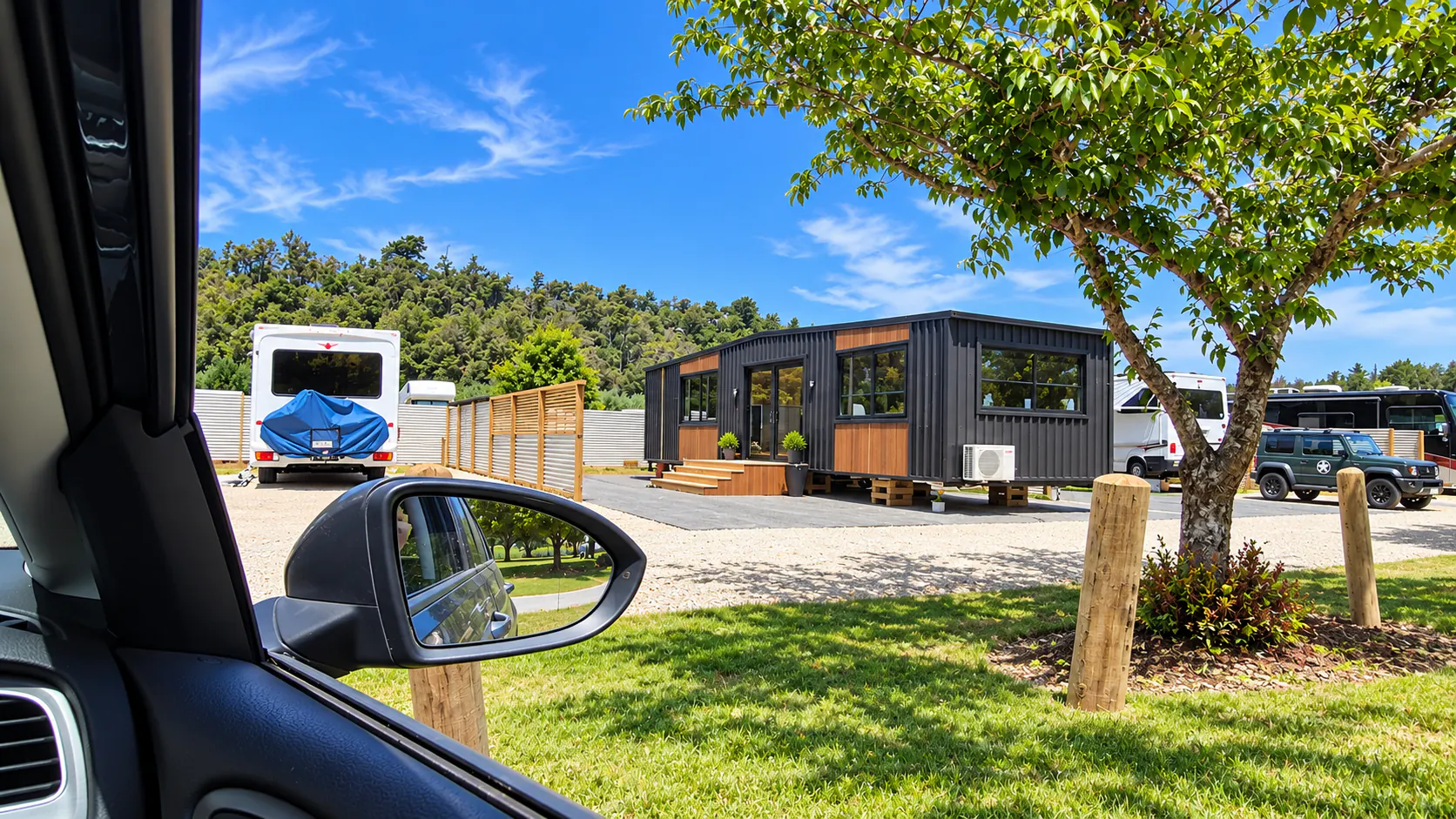 Charcoal tiny home seen from a vehicle window in the sunny park at Kaiteriteri